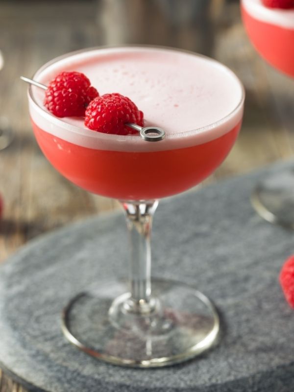 two glasses filled with raspberry martinis and garnished with fresh raspberries