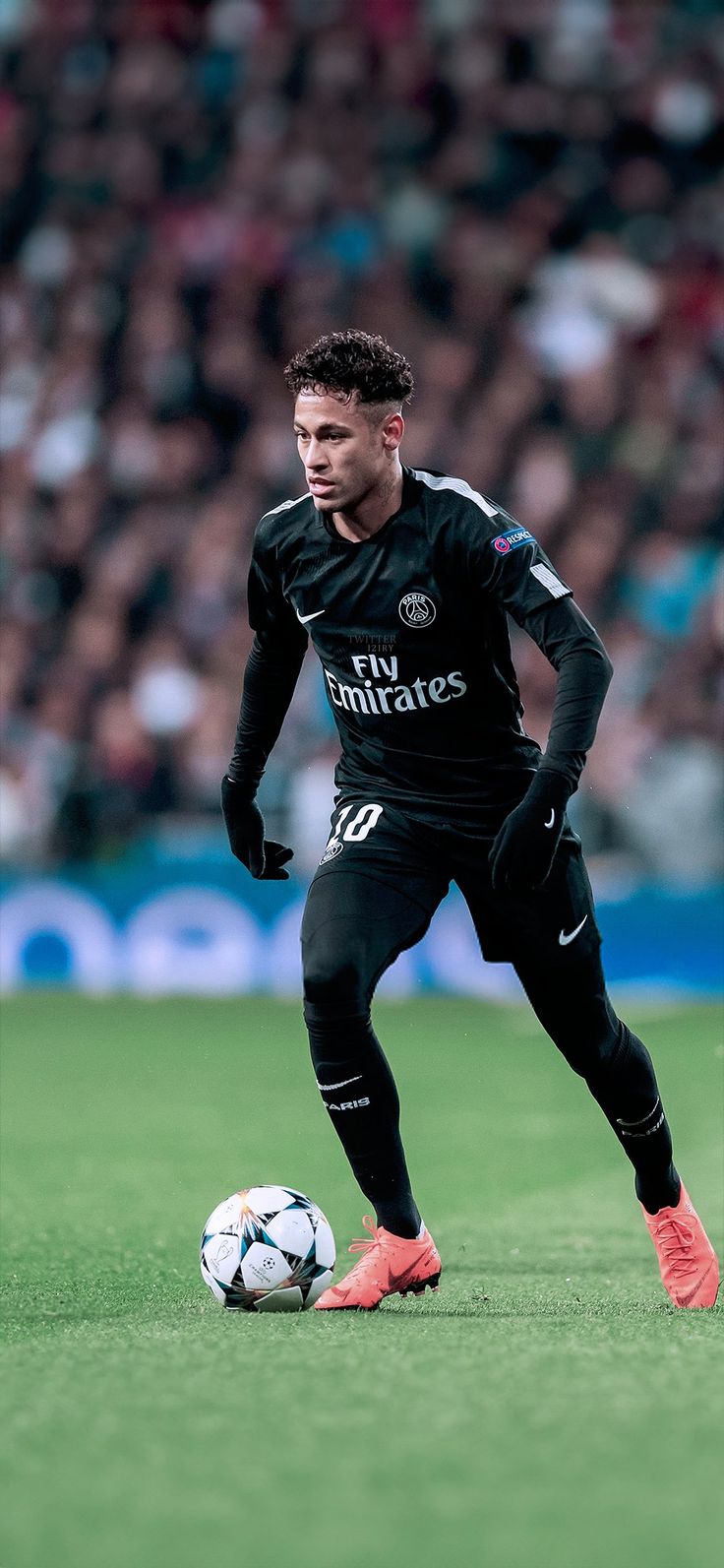 a soccer player in action on the field during a game with an audience behind him