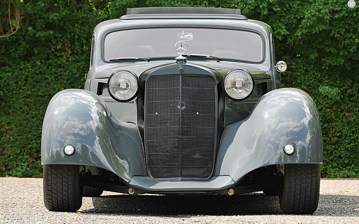 an old car is parked in front of some trees