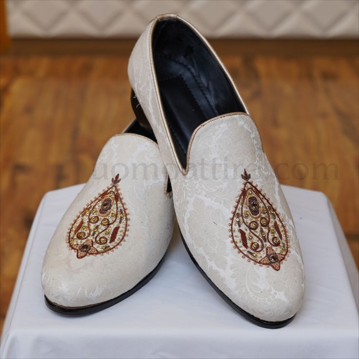 pair of white embroidered shoes sitting on top of a table