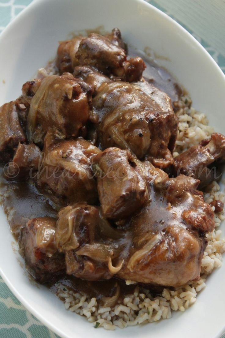 a white bowl filled with rice and meat covered in gravy on top of a table