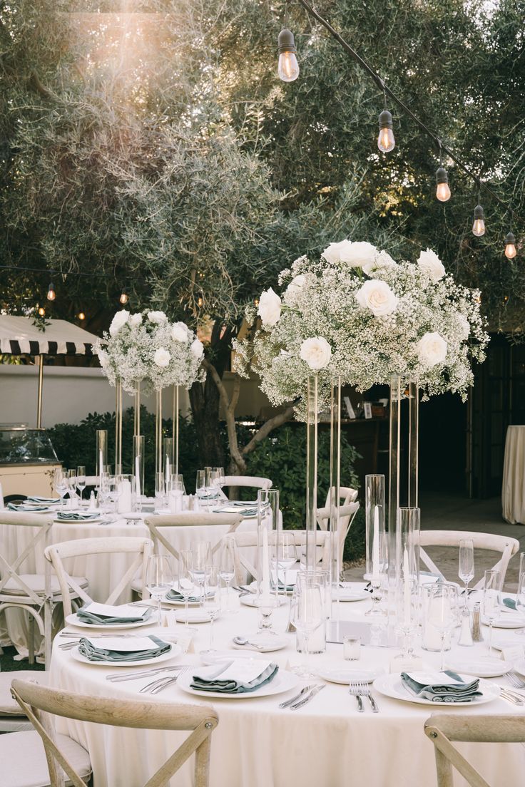 the tables are set with white flowers in vases and place settings for guests to sit at