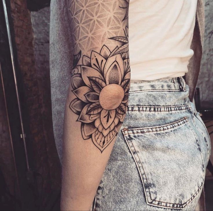 a woman's arm with a flower tattoo on the left side of her arm