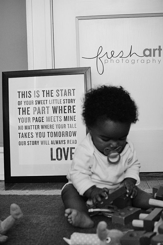 a black and white photo of a baby on the floor playing with toy cars in front of a sign that reads, this is the start