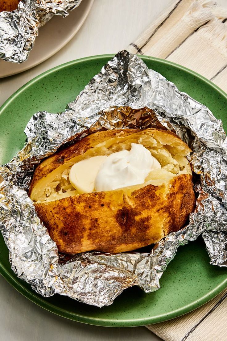 baked potatoes in foil on a green plate