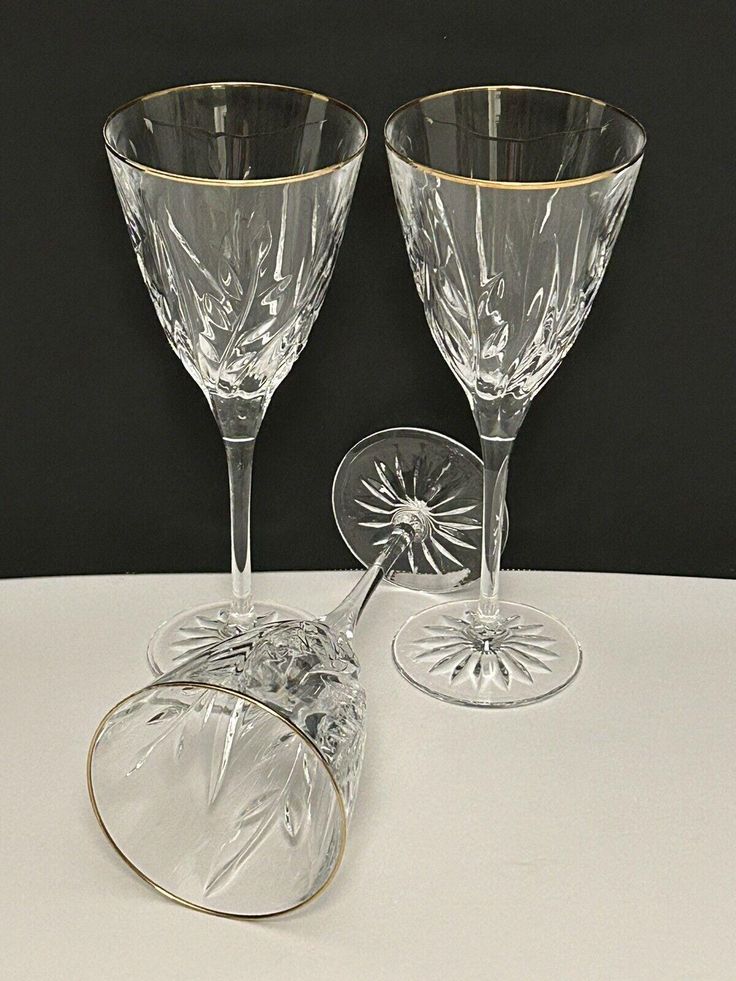 two clear wine glasses sitting next to each other on a white tableclothed surface