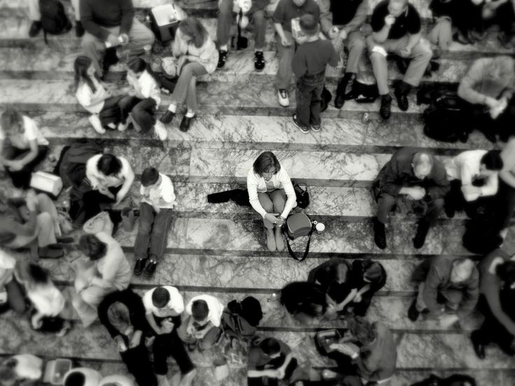 a group of people sitting on the steps in front of some stairs with one person holding a cell phone