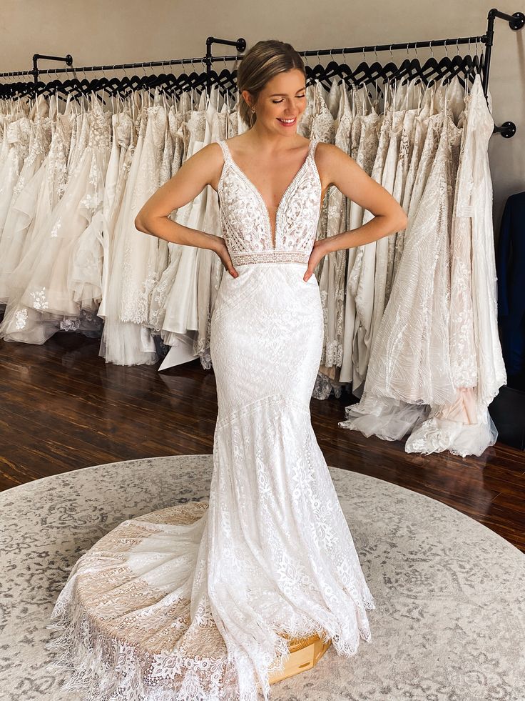 a woman standing in front of a rack of wedding dresses