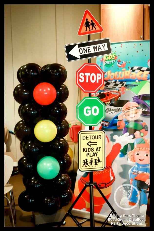 a traffic light sitting next to a street sign with balloons in the shape of stop signs