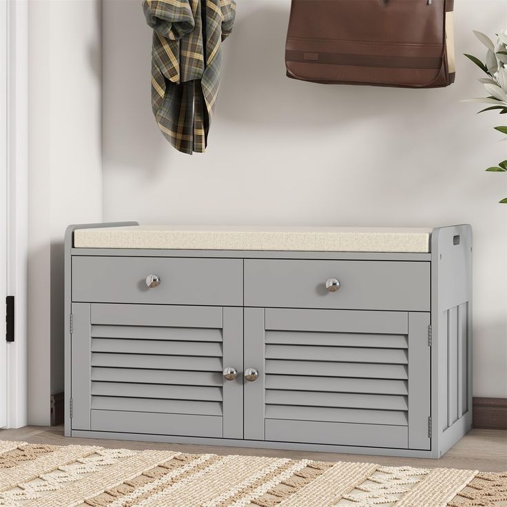 a gray bench sitting next to a purse and coat rack