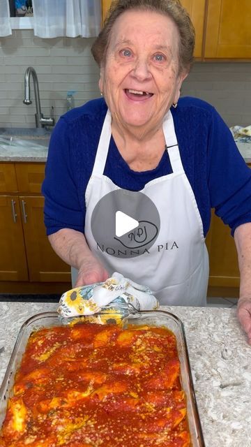 an older woman is making a pizza in the kitchen