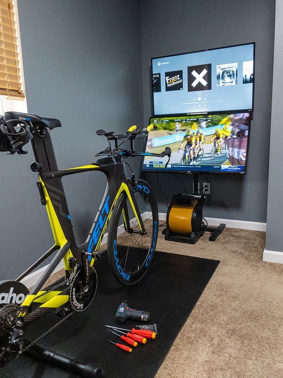 a bicycle is parked in front of a flat screen tv with tools on the floor