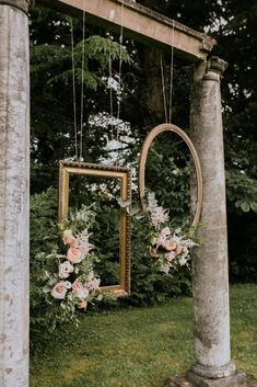 an old photo frame with flowers hanging from it's sides in front of a wooden pole