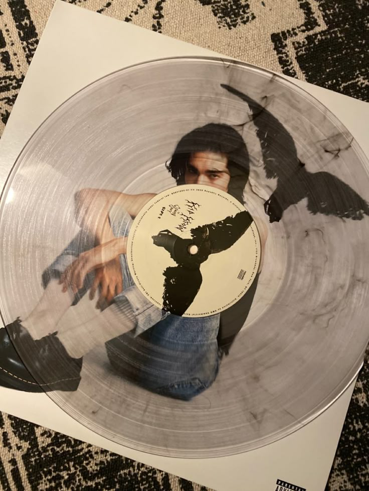 an image of a man with a bird on his head in a silver vinyl record