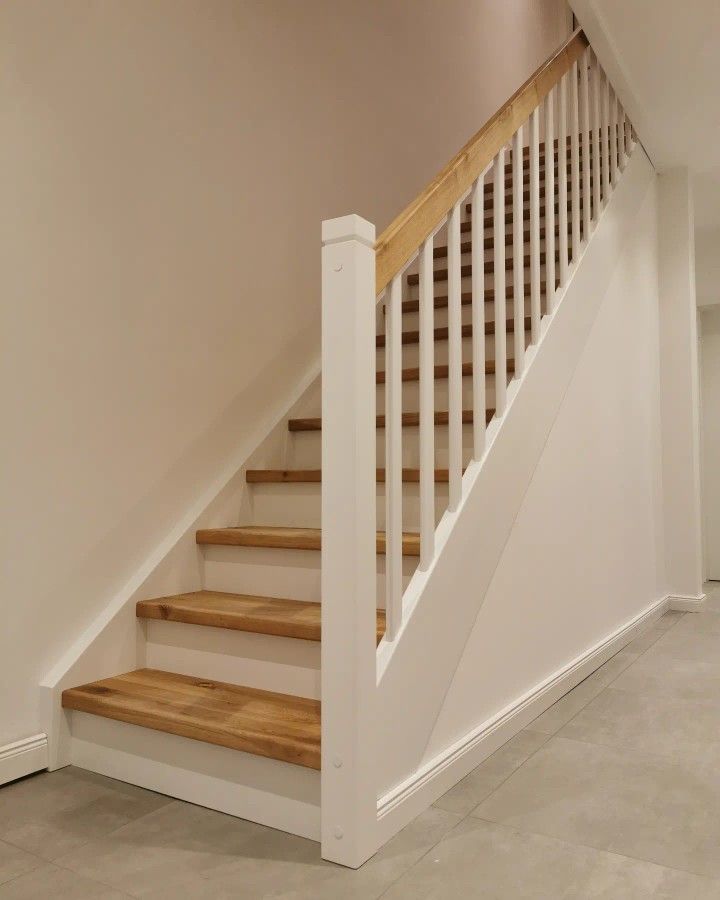 a white staircase with wooden handrails in an empty room