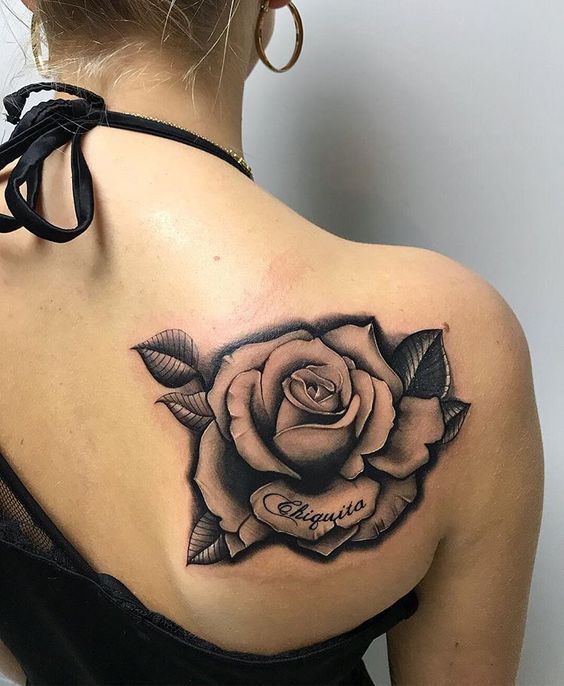 a woman with a rose tattoo on her upper back shoulder and chest, in black and white