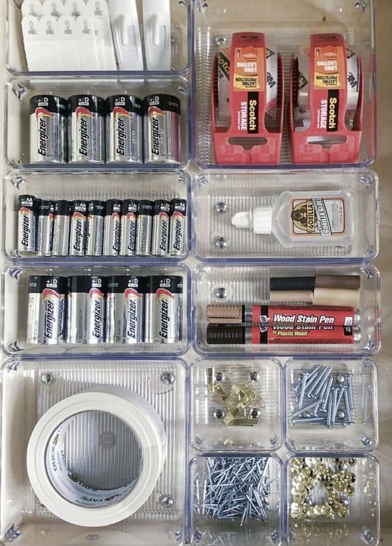 an organized storage drawer filled with batteries and screws