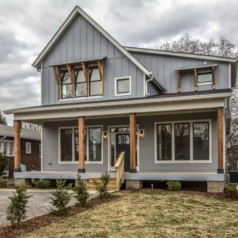 a gray house sitting on top of a lush green field