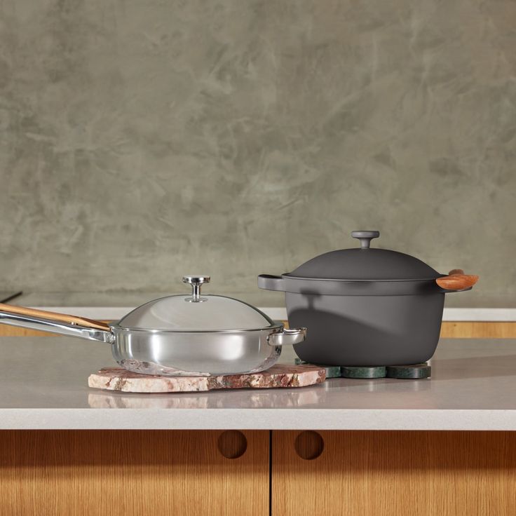 two pots and pans sitting on top of a counter