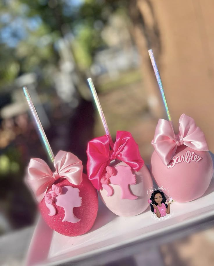 three pink and white cake pops with bows on them