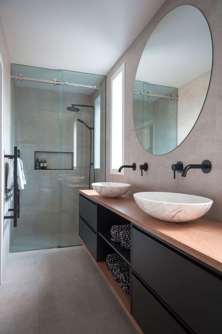 a bathroom with two sinks and a large round mirror above the sink in front of it