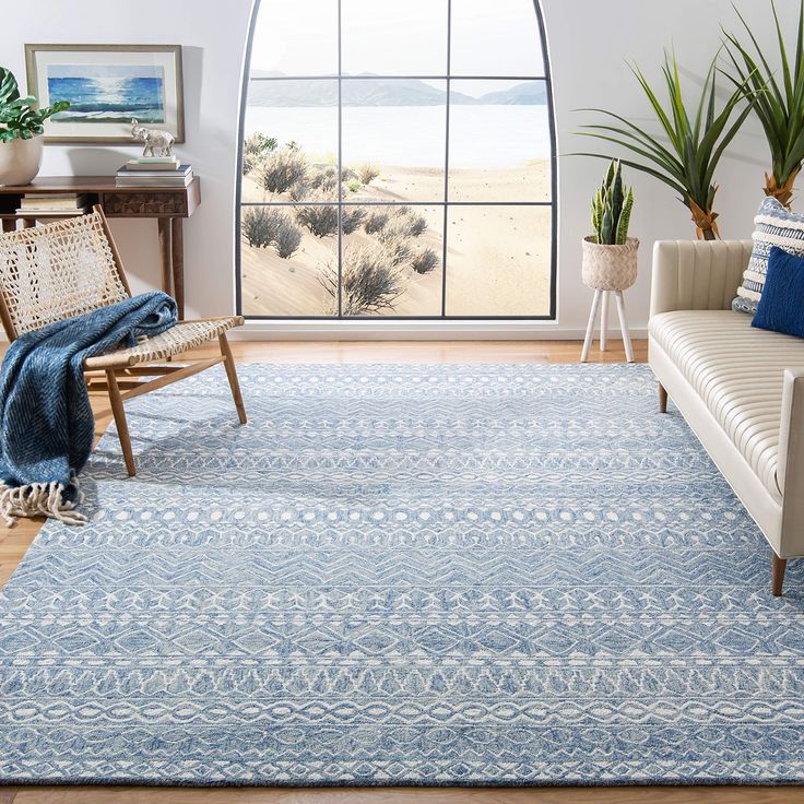 a living room with a couch, chair and rug in front of a large window