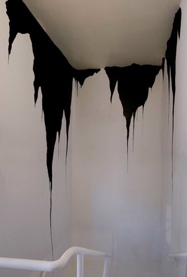 a room with black and white paint dripping from the ceiling to the walls, in front of a stair rail