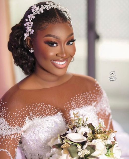 a woman wearing a bridal gown holding a bouquet of flowers and smiling at the camera