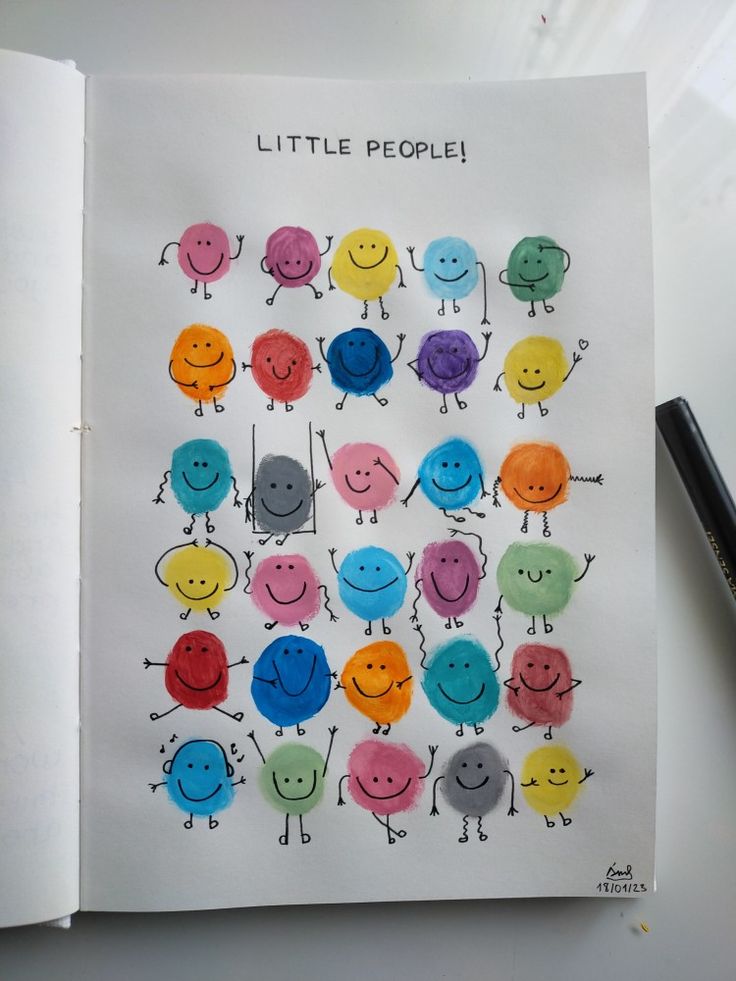 an open book with drawings of little people on it and a pen next to it