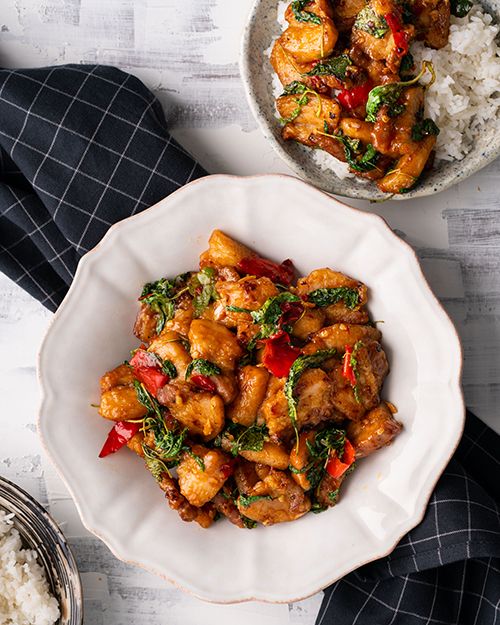 two bowls filled with chicken and vegetables next to rice