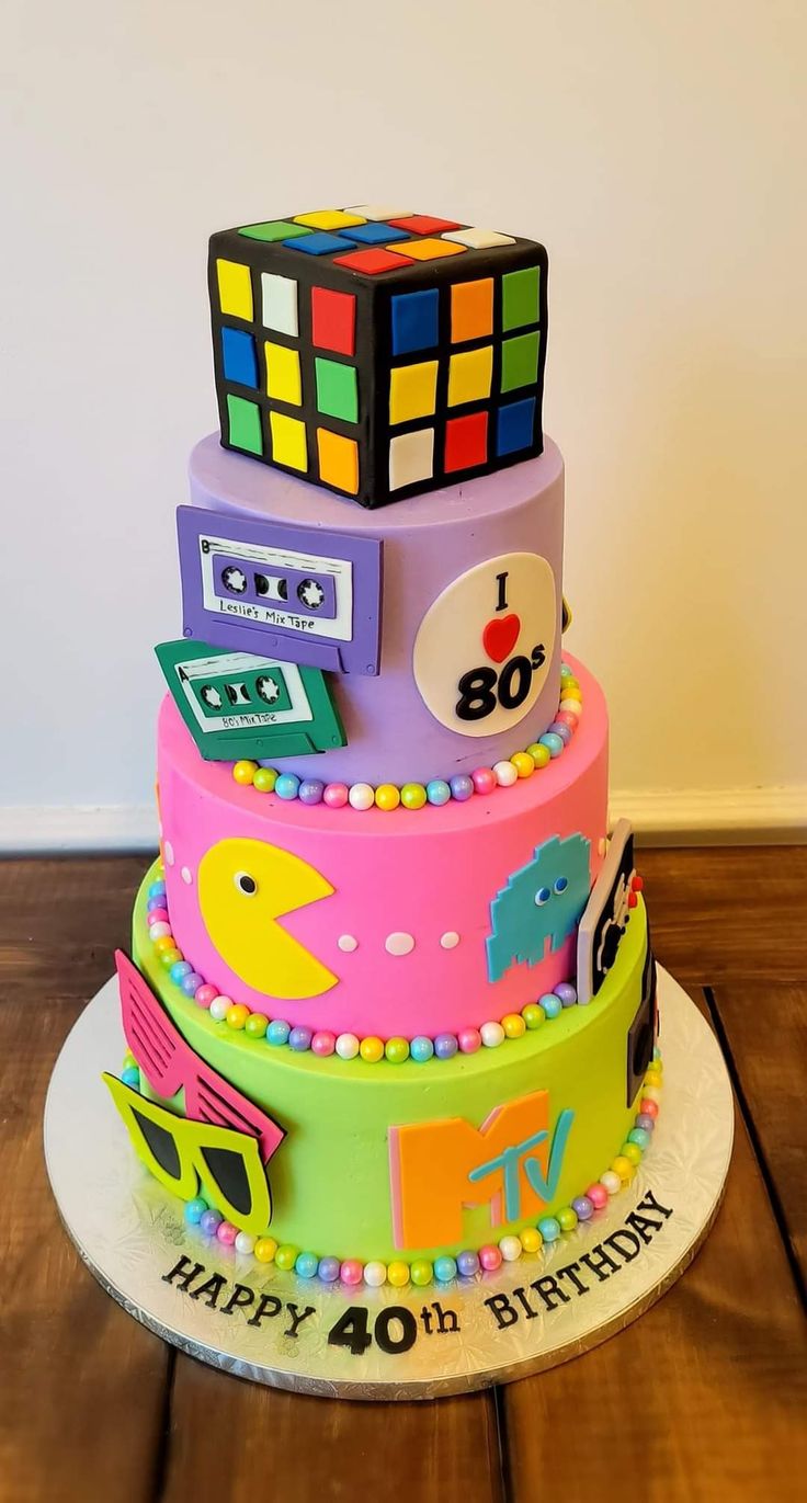 a multi - tiered birthday cake decorated with rubiks and other items on a wooden table