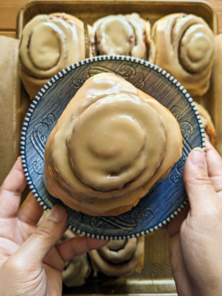 a person holding a plate with some kind of pastry on it in front of other pastries