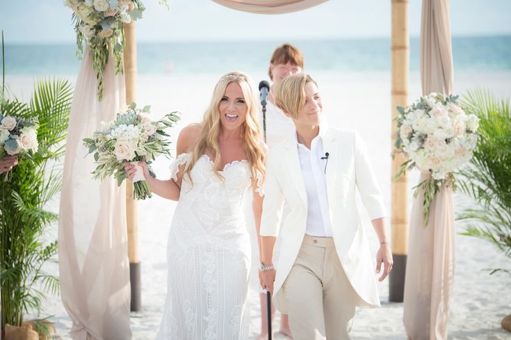 a bride and groom walk down the aisle at their wedding ceremony on the beach in front of an ocean