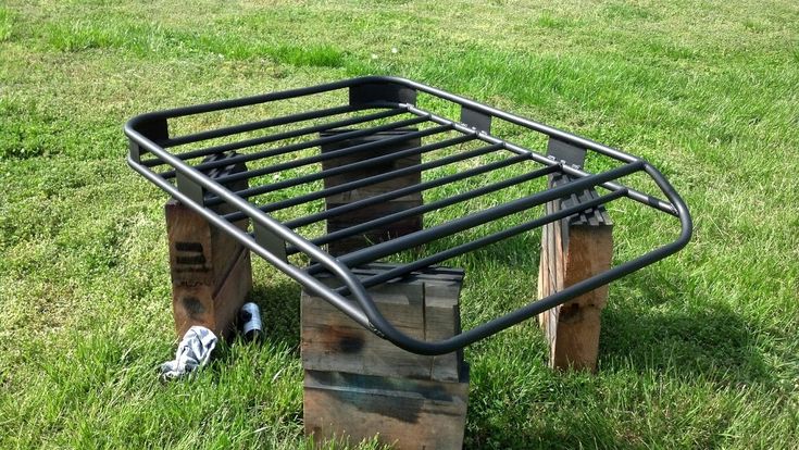 a metal bed frame sitting on top of wooden pallets in the middle of grass