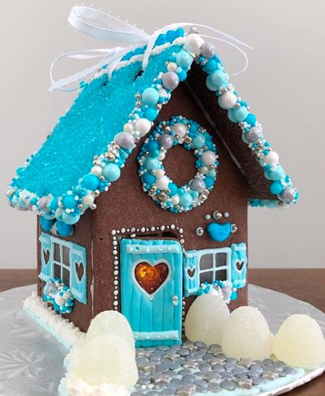 a gingerbread house decorated with blue icing and white frosting on a plate