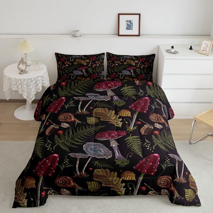 a bed covered in a black comforter with mushrooms and leaves on it, next to a night stand