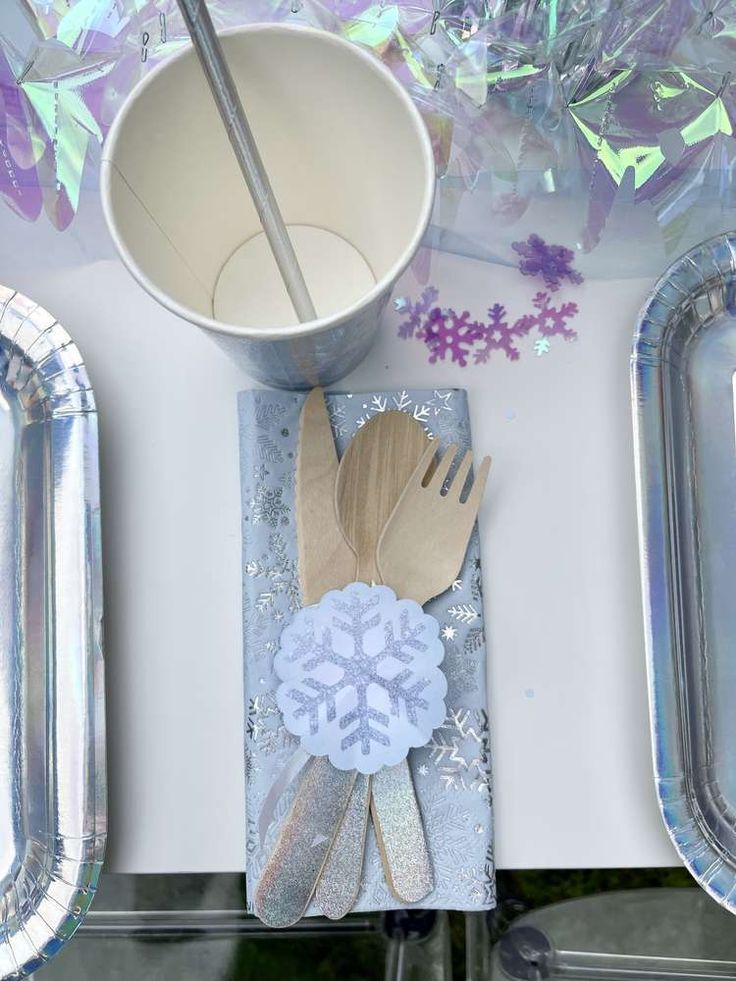 a table topped with silver trays filled with paper plates and utensil holders