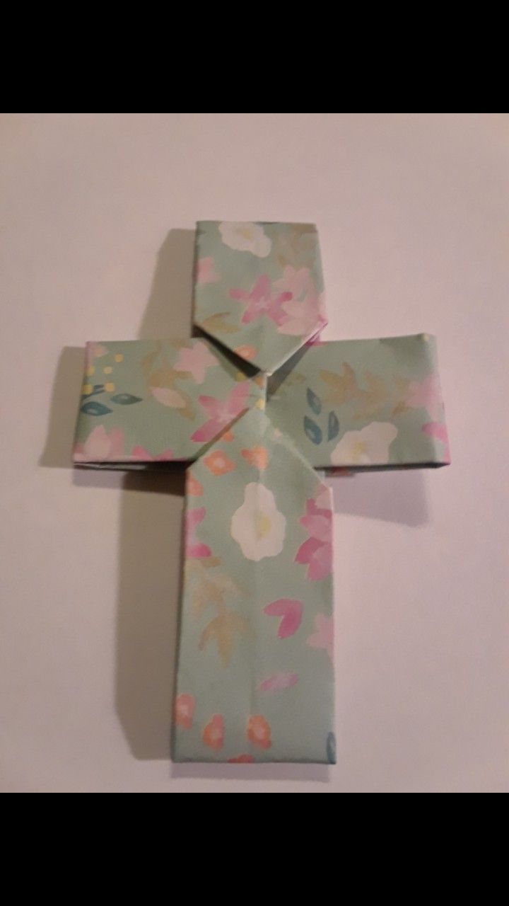 an origami cross made out of paper with flowers on it's sides