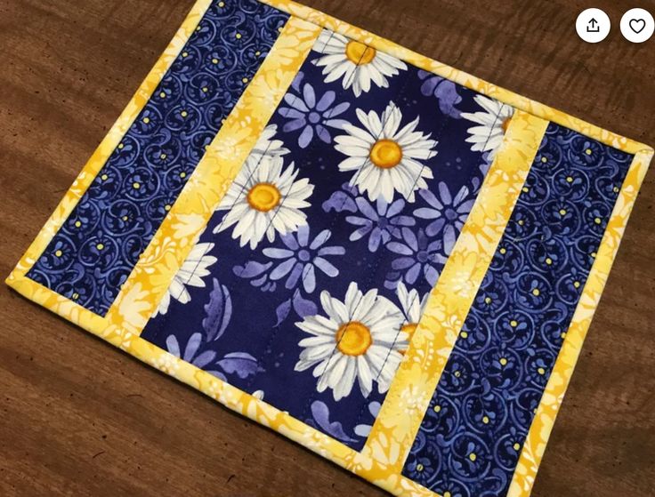 a blue and yellow placemat with white daisies on the edge, sitting on a wooden table