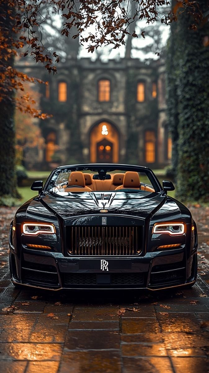 a black rolls royce parked in front of a house at night with the lights on