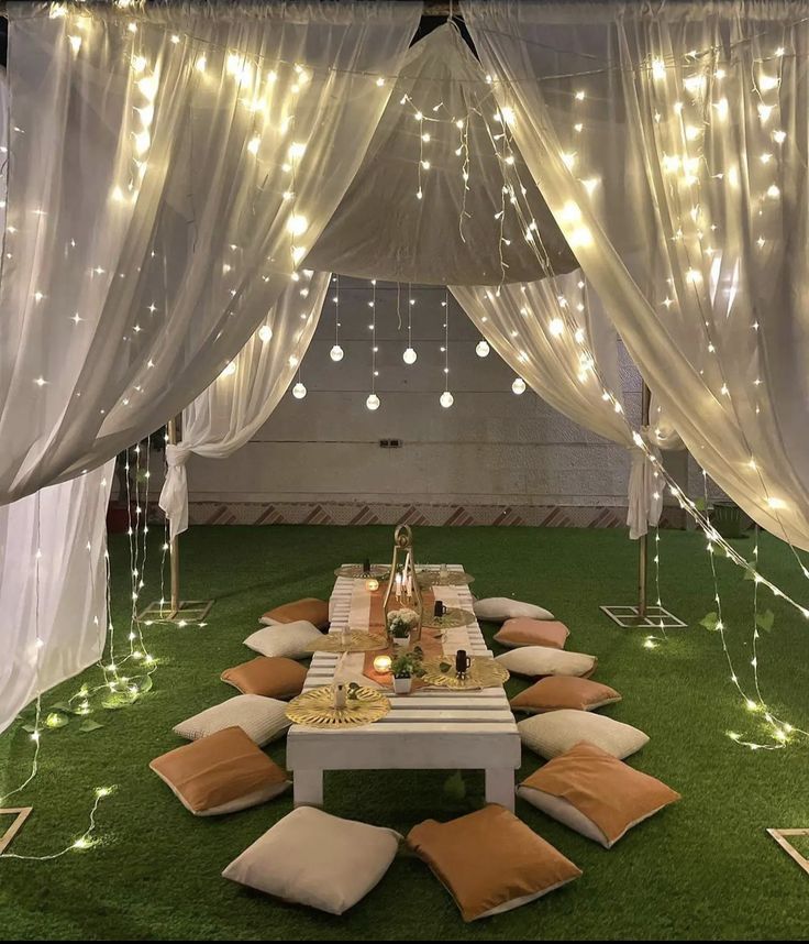 a table with pillows and lights on it in the middle of an indoor area that is decorated for a party