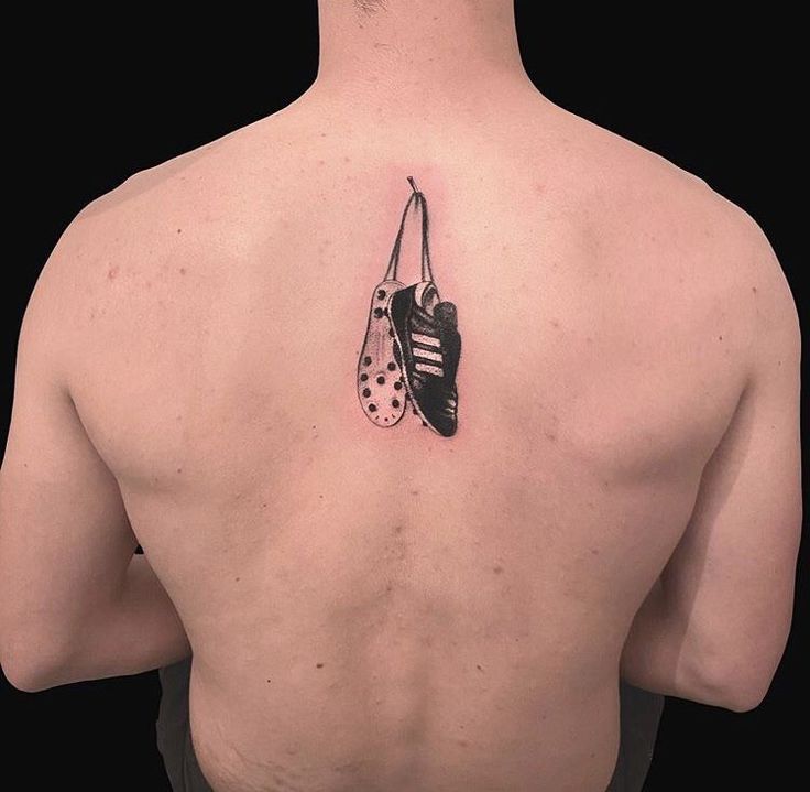 the back of a man with a tattoo on his chest and an ornament hanging from it