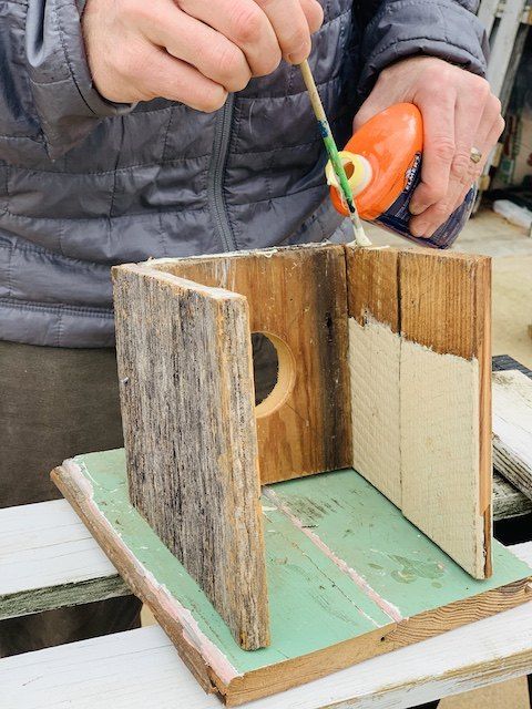 a person using a toothbrush to brush the inside of a wooden box with paint