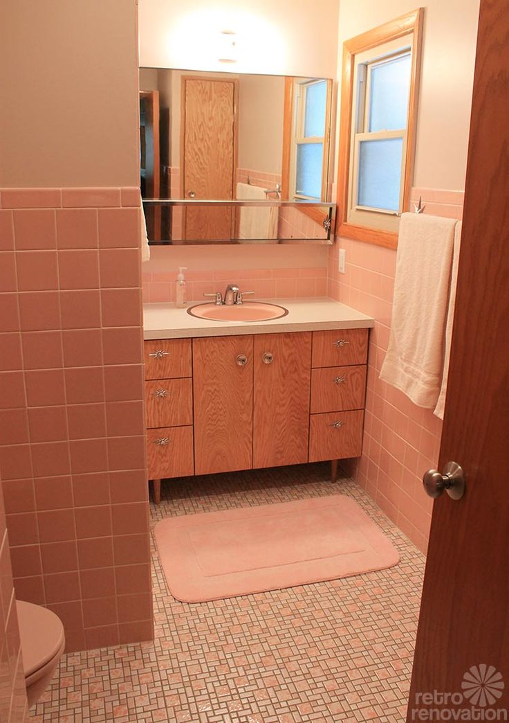 a bathroom with pink tile and wooden cabinets