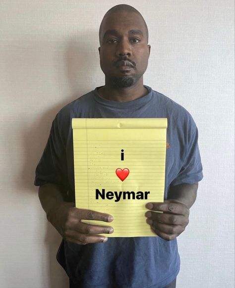 a man holding up a yellow piece of paper with i love neymar written on it