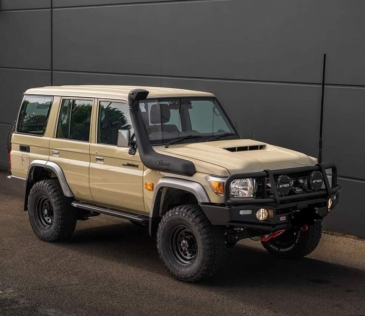 an off - road vehicle is parked in front of a building with a black wall