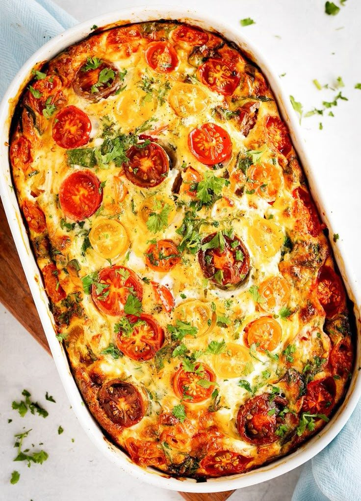 a casserole dish with tomatoes, cheese and herbs