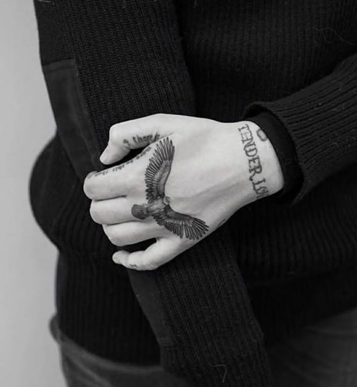 a person with a bird tattoo on their arm and wrist, holding onto her hand