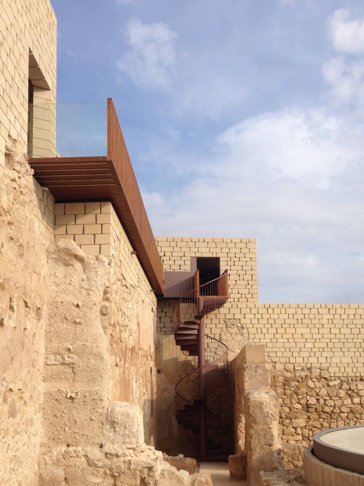 a stone building with a spiral staircase going up it's side to the sky