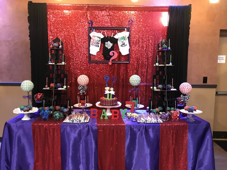 a table topped with lots of cakes and desserts next to a red wall covered in sequins